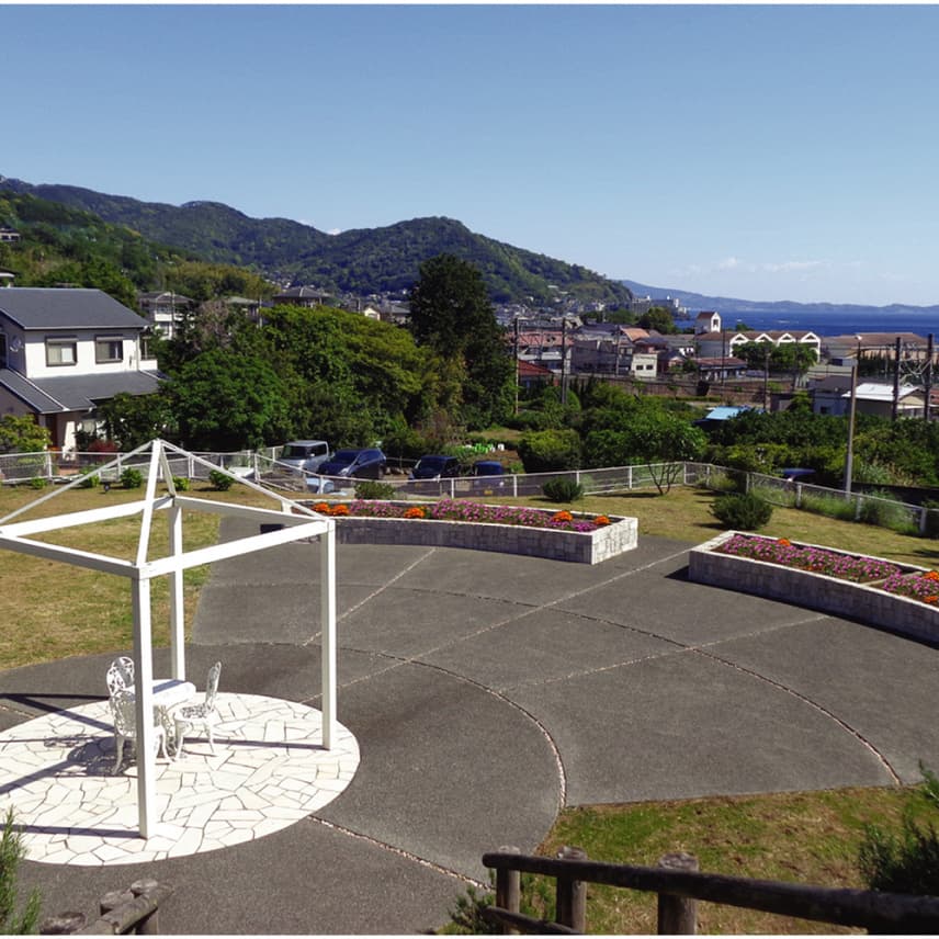 施設の庭園・外構。山々を背景にした広い敷地に遊歩道と花壇が整備されている。