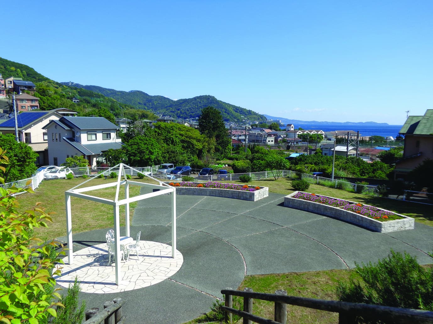 施設の庭園。白いパーゴラと花壇、海を望む景観が特徴